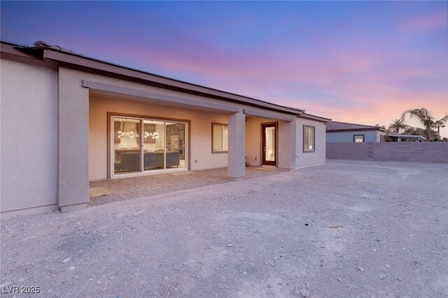 back house at dusk with a patio area