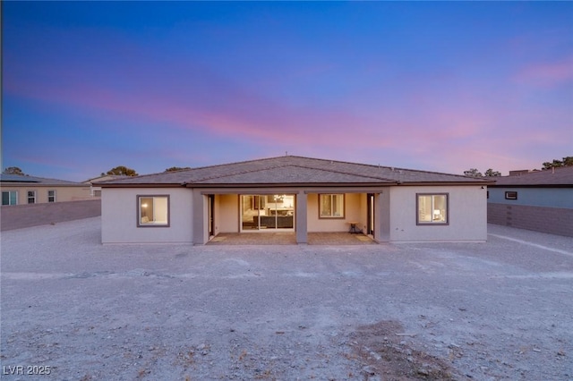 back house at dusk featuring a patio