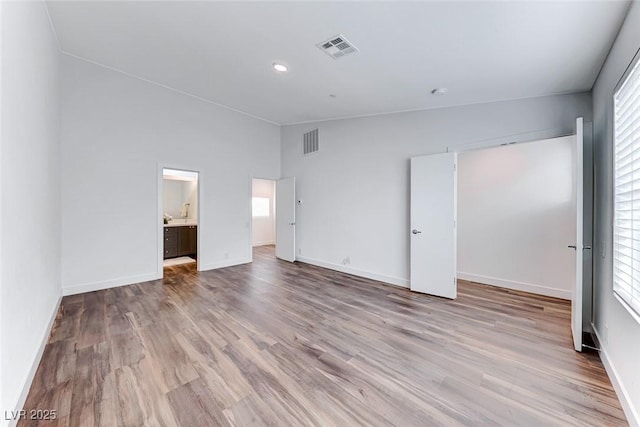 unfurnished bedroom featuring multiple windows, vaulted ceiling, and light hardwood / wood-style flooring