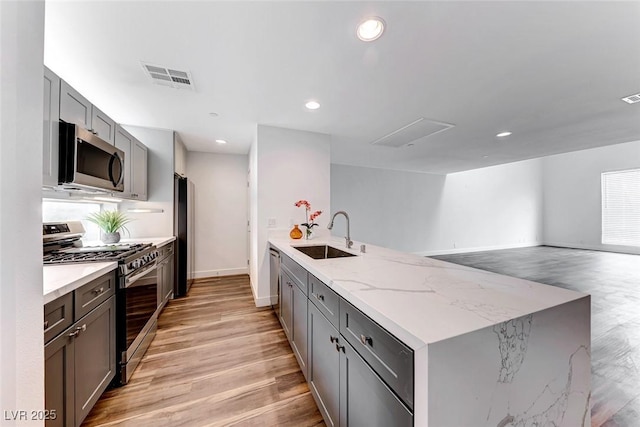 kitchen featuring gray cabinets, appliances with stainless steel finishes, sink, light stone countertops, and light hardwood / wood-style flooring