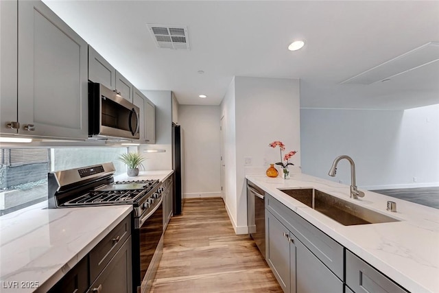 kitchen featuring sink, gray cabinets, stainless steel appliances, and light stone countertops