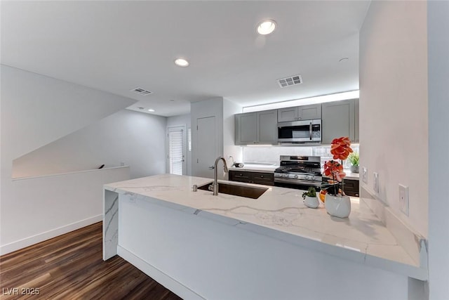 kitchen featuring sink, gray cabinetry, kitchen peninsula, stainless steel appliances, and light stone countertops