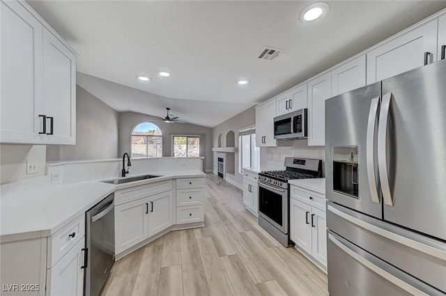 kitchen featuring lofted ceiling, stainless steel appliances, sink, and white cabinets