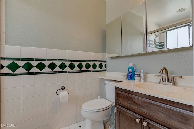 bathroom with vanity, a shower, tile walls, and toilet