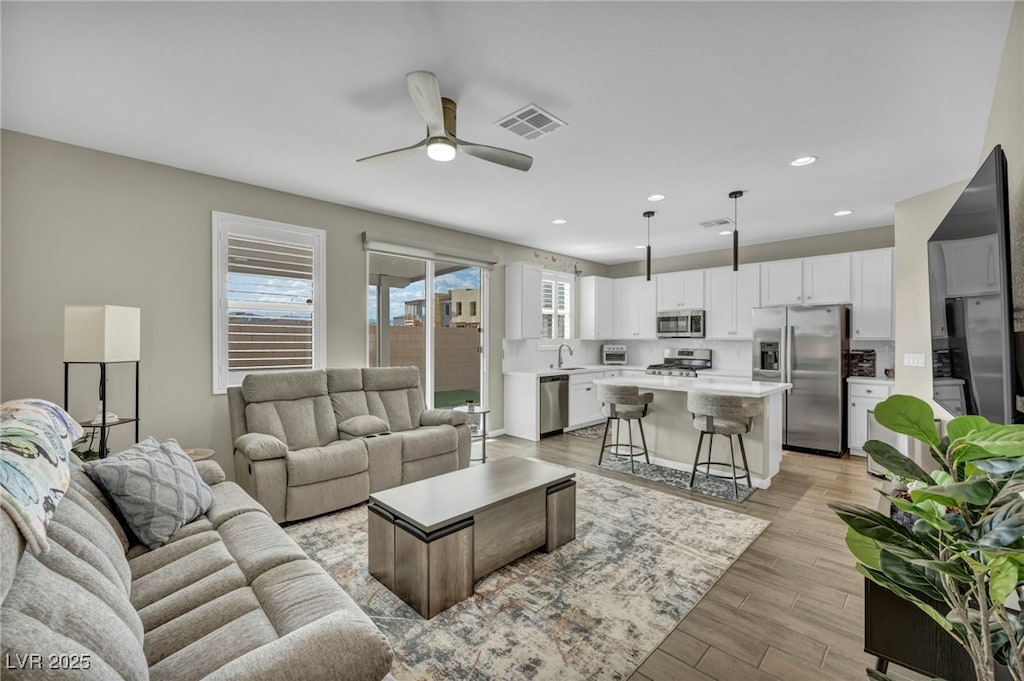 living room with sink, ceiling fan, and light hardwood / wood-style flooring