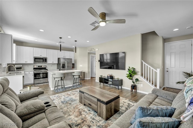 living room featuring ceiling fan, sink, and light hardwood / wood-style floors