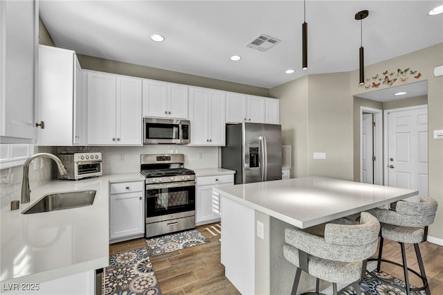 kitchen with sink, white cabinetry, tasteful backsplash, appliances with stainless steel finishes, and pendant lighting