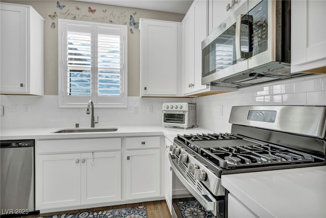 kitchen featuring white cabinetry, appliances with stainless steel finishes, sink, and tasteful backsplash