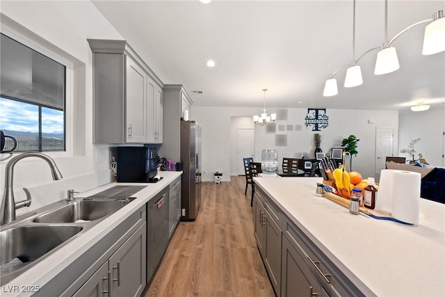 kitchen featuring gray cabinets, appliances with stainless steel finishes, sink, hanging light fixtures, and light hardwood / wood-style flooring