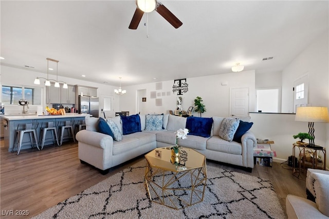 living room featuring ceiling fan with notable chandelier and light hardwood / wood-style floors