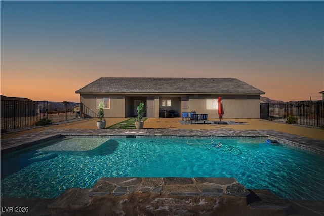 pool at dusk featuring a patio