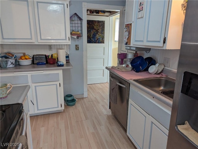 kitchen featuring stainless steel appliances, white cabinetry, sink, and light hardwood / wood-style flooring