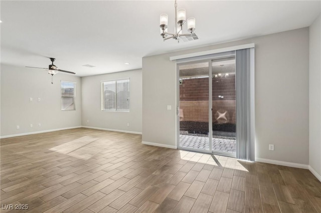 empty room with ceiling fan with notable chandelier and wood-type flooring