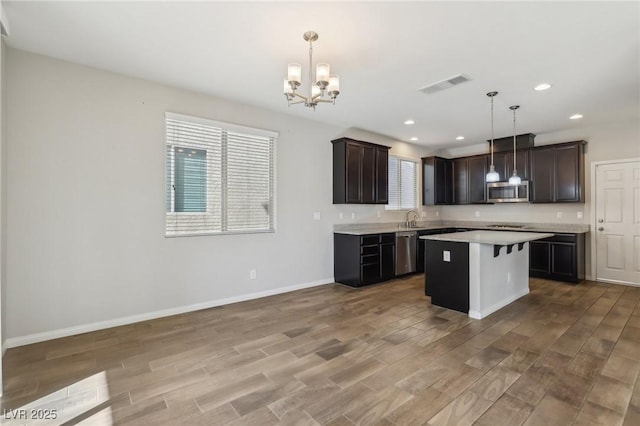 kitchen featuring a kitchen island, sink, a kitchen breakfast bar, hanging light fixtures, and stainless steel appliances