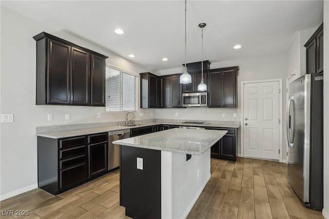 kitchen featuring appliances with stainless steel finishes, pendant lighting, sink, a center island, and light stone countertops