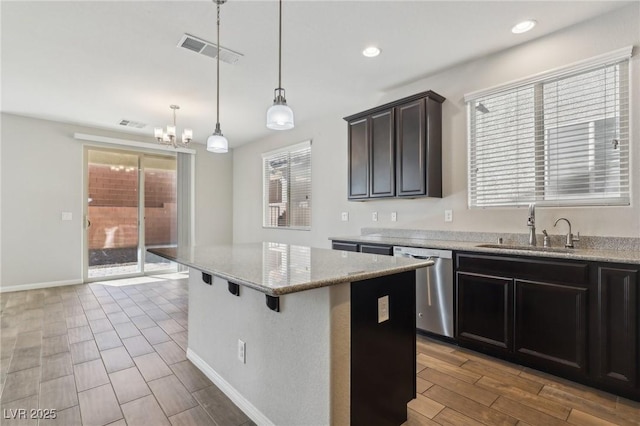 kitchen with a kitchen island, decorative light fixtures, dishwasher, sink, and light stone counters