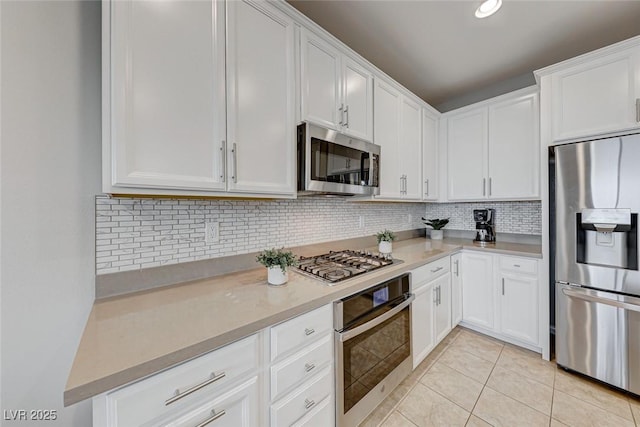 kitchen with tasteful backsplash, white cabinetry, appliances with stainless steel finishes, and light tile patterned flooring