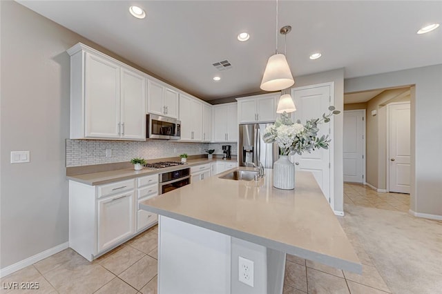 kitchen featuring stainless steel appliances, hanging light fixtures, a kitchen island with sink, and white cabinets