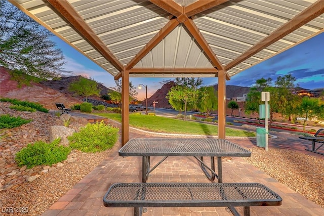 patio terrace at dusk with a mountain view and a lawn