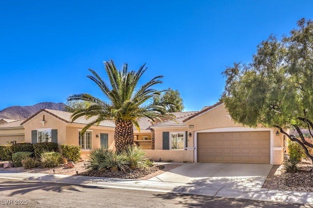 view of front of home featuring a tile roof, stucco siding, concrete driveway, a mountain view, and a garage