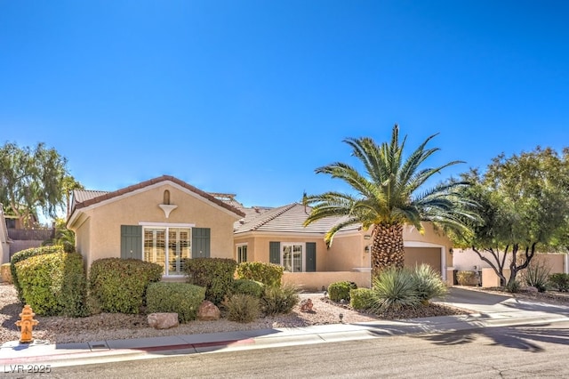 view of front of property with driveway, an attached garage, a tile roof, and stucco siding