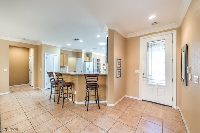 foyer entrance featuring light tile patterned flooring, visible vents, and crown molding