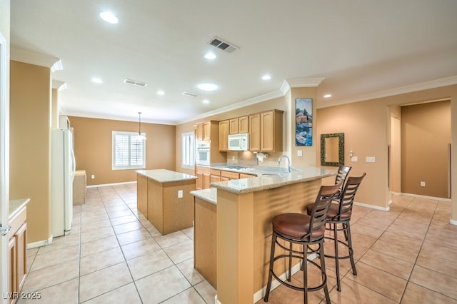 kitchen featuring white appliances, visible vents, a kitchen island, and a peninsula