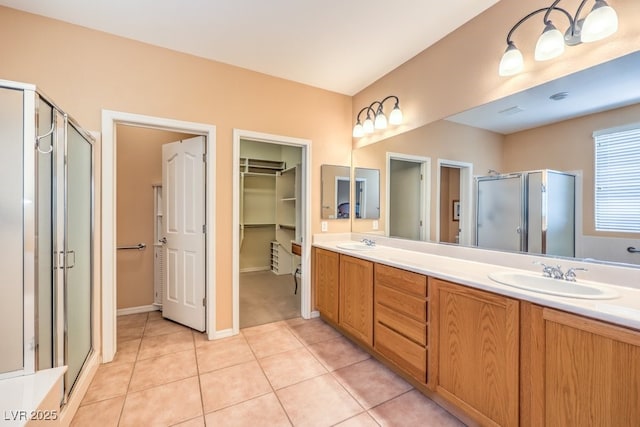 bathroom featuring a stall shower, double vanity, a sink, and tile patterned floors