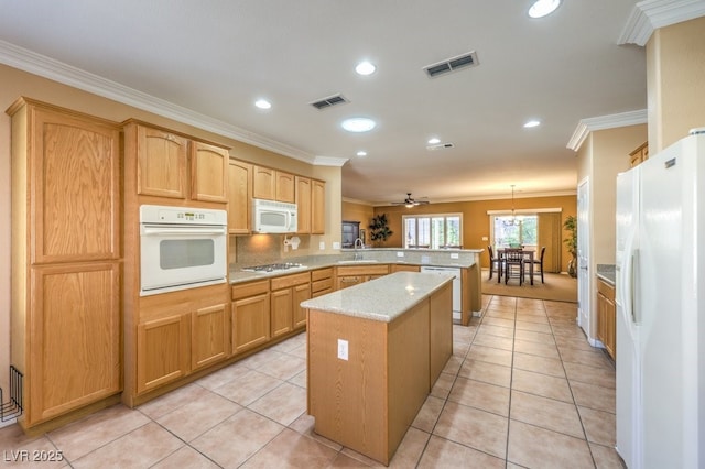 kitchen with a peninsula, white appliances, visible vents, and a sink