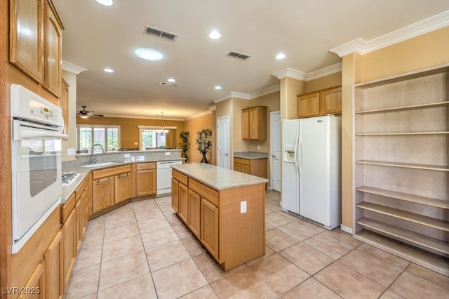 kitchen featuring white appliances, visible vents, a kitchen island, a peninsula, and a sink