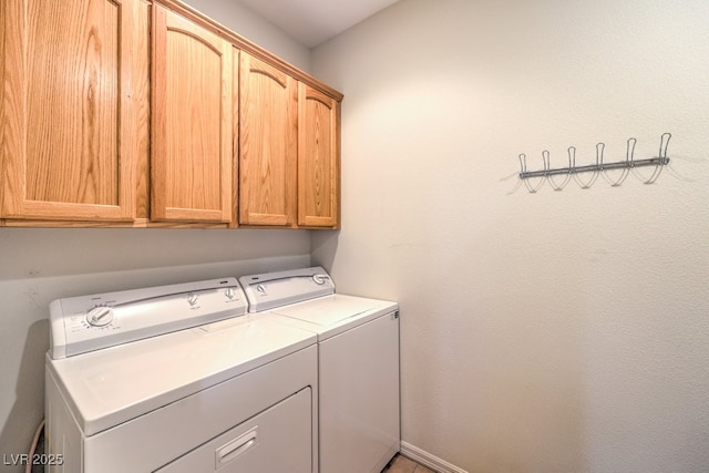 washroom with washer and dryer, cabinet space, and baseboards