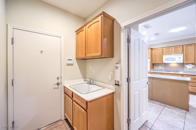 clothes washing area with light tile patterned floors, crown molding, visible vents, and a sink