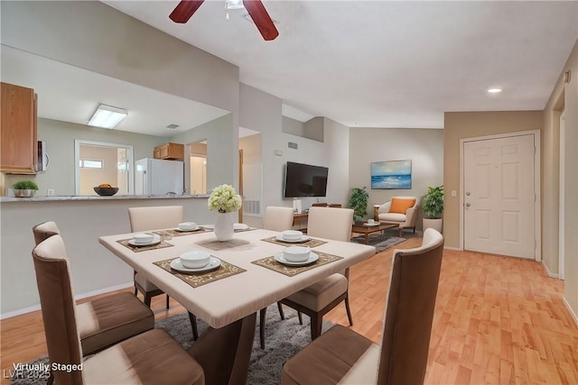 dining area with ceiling fan, lofted ceiling, and light hardwood / wood-style floors