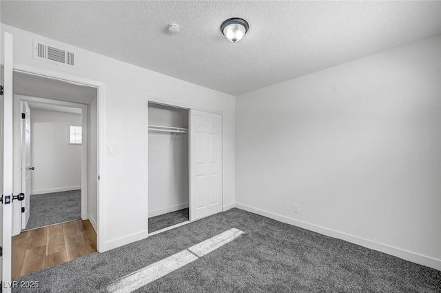 unfurnished bedroom featuring a closet, a textured ceiling, and dark colored carpet