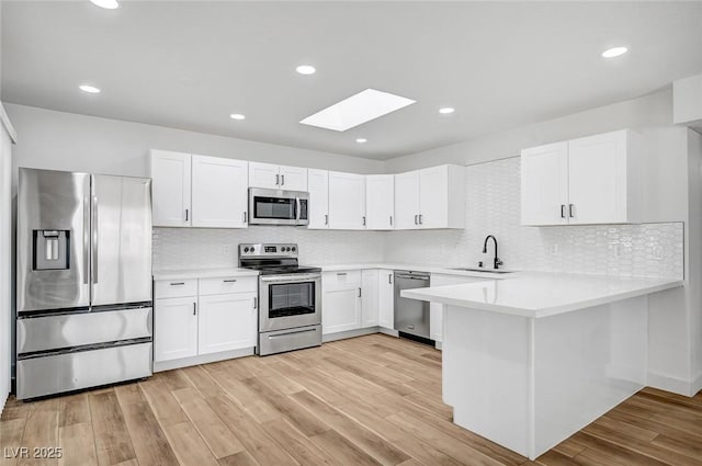 kitchen featuring appliances with stainless steel finishes, sink, light wood-type flooring, and white cabinets