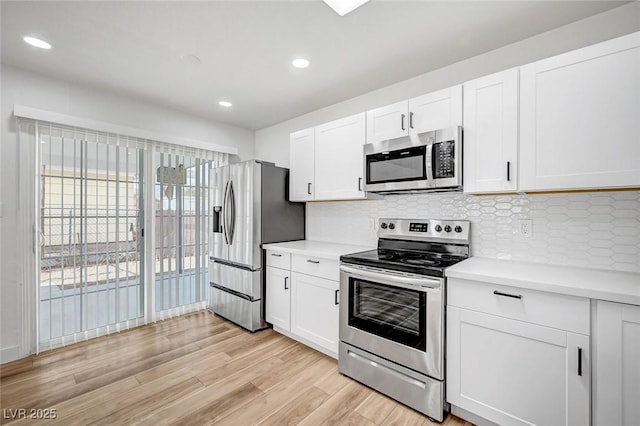 kitchen with white cabinetry, stainless steel appliances, light hardwood / wood-style floors, and decorative backsplash