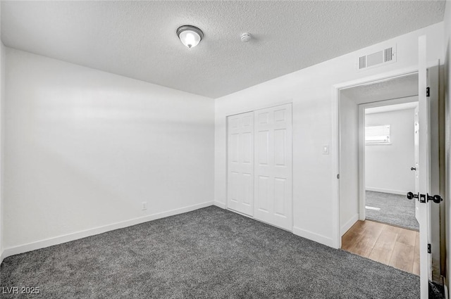 unfurnished bedroom featuring a closet, dark carpet, and a textured ceiling