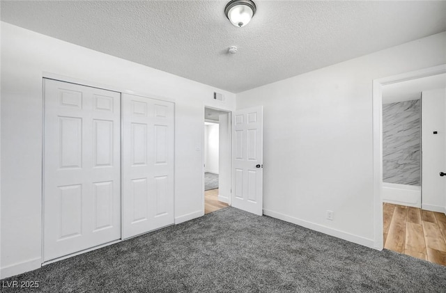 unfurnished bedroom with dark colored carpet, a textured ceiling, and a closet