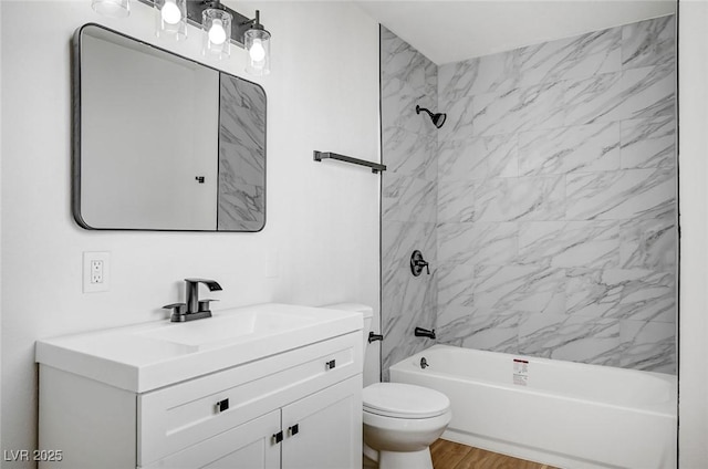 full bathroom featuring tiled shower / bath combo, vanity, hardwood / wood-style flooring, and toilet