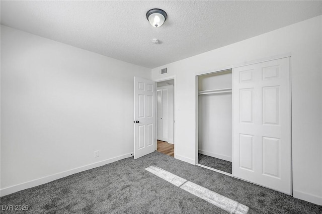 unfurnished bedroom featuring a closet, dark carpet, and a textured ceiling