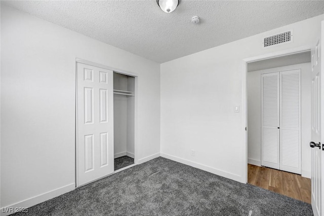 unfurnished bedroom with a closet, dark carpet, and a textured ceiling