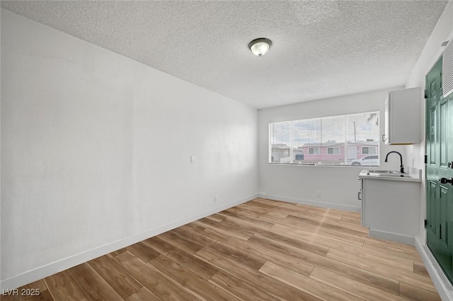 interior space featuring sink, a textured ceiling, and light hardwood / wood-style flooring