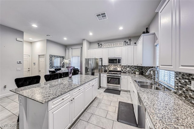 kitchen featuring a breakfast bar, sink, white cabinets, a center island, and stainless steel appliances