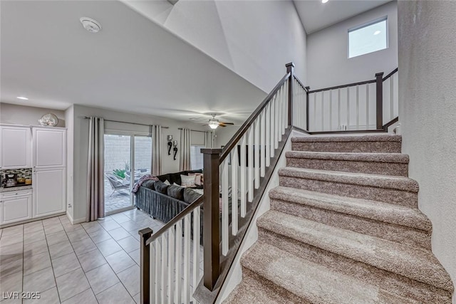 stairway with tile patterned flooring, a high ceiling, and ceiling fan