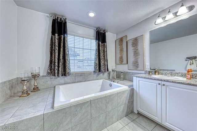 bathroom with tile patterned flooring, vanity, and tiled bath