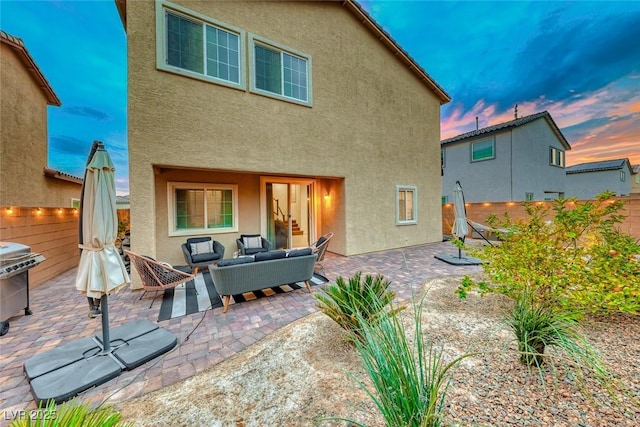 back house at dusk featuring outdoor lounge area and a patio area