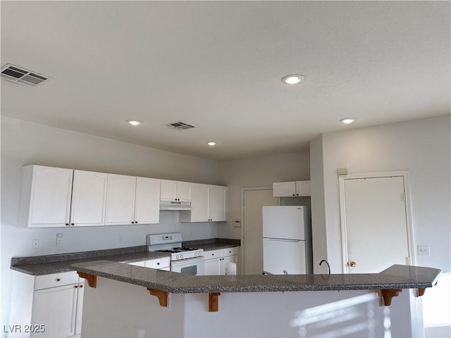 kitchen with white appliances, a kitchen breakfast bar, and white cabinets