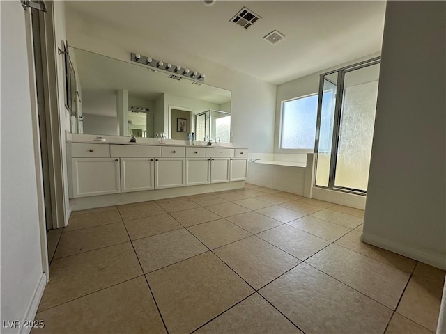 bathroom with vanity, a relaxing tiled tub, and tile patterned floors