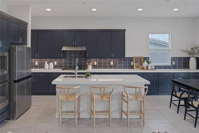 kitchen featuring tasteful backsplash, an island with sink, and a kitchen bar