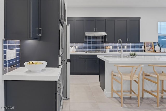 kitchen with decorative backsplash, sink, a breakfast bar area, and gas stovetop